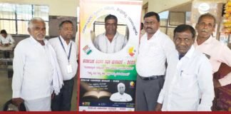 A group of people taking a selfie in front of a banner promoting the Karnataka assembly elections.