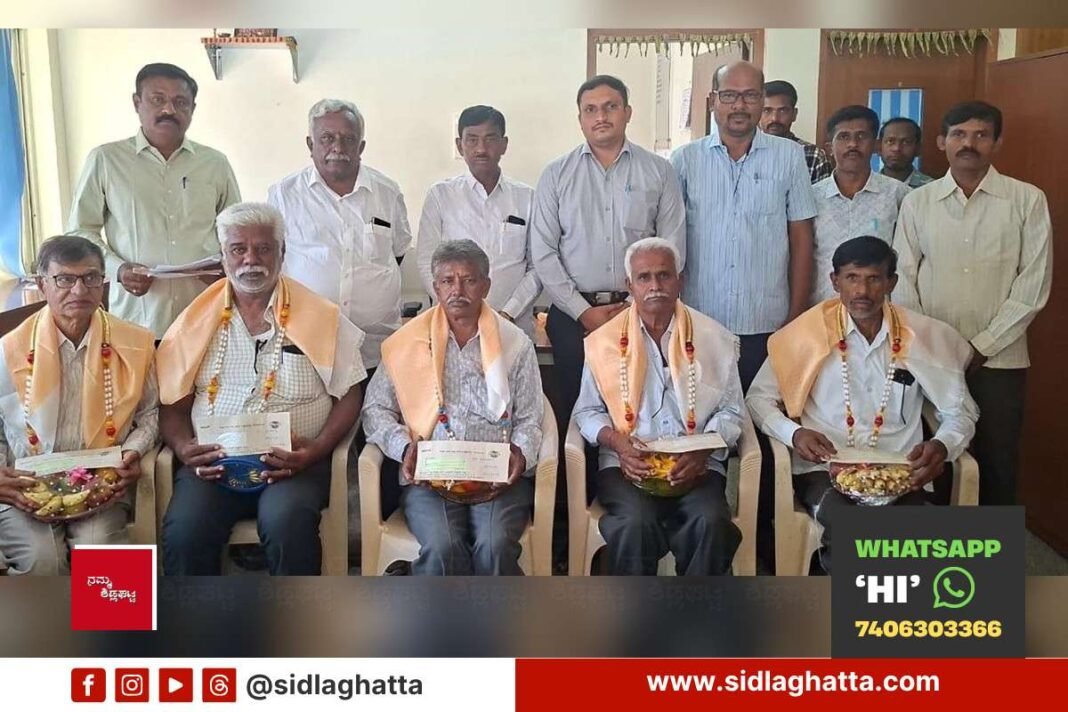 CHIMUL director Bunk Muniyappa and officials with dairy farmers and retired society secretaries receiving cattle insurance and honorarium cheques