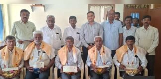 CHIMUL director Bunk Muniyappa and officials with dairy farmers and retired society secretaries receiving cattle insurance and honorarium cheques