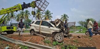 Damaged car being lifted by crane after falling into roadside drain near Handiganala lake, with bent crash barrier