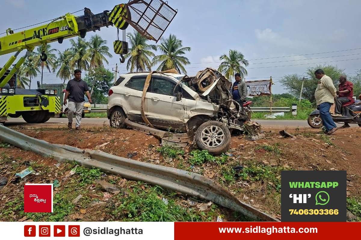 Sidlaghatta-Handiganala-Car-Falls-Into-Roadside-Drain Damaged car being lifted by crane after falling into roadside drain near Handiganala lake, with bent crash barrier