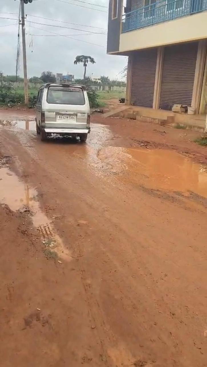 Vehicle driving through a muddy, puddled road in a residential layout after rain